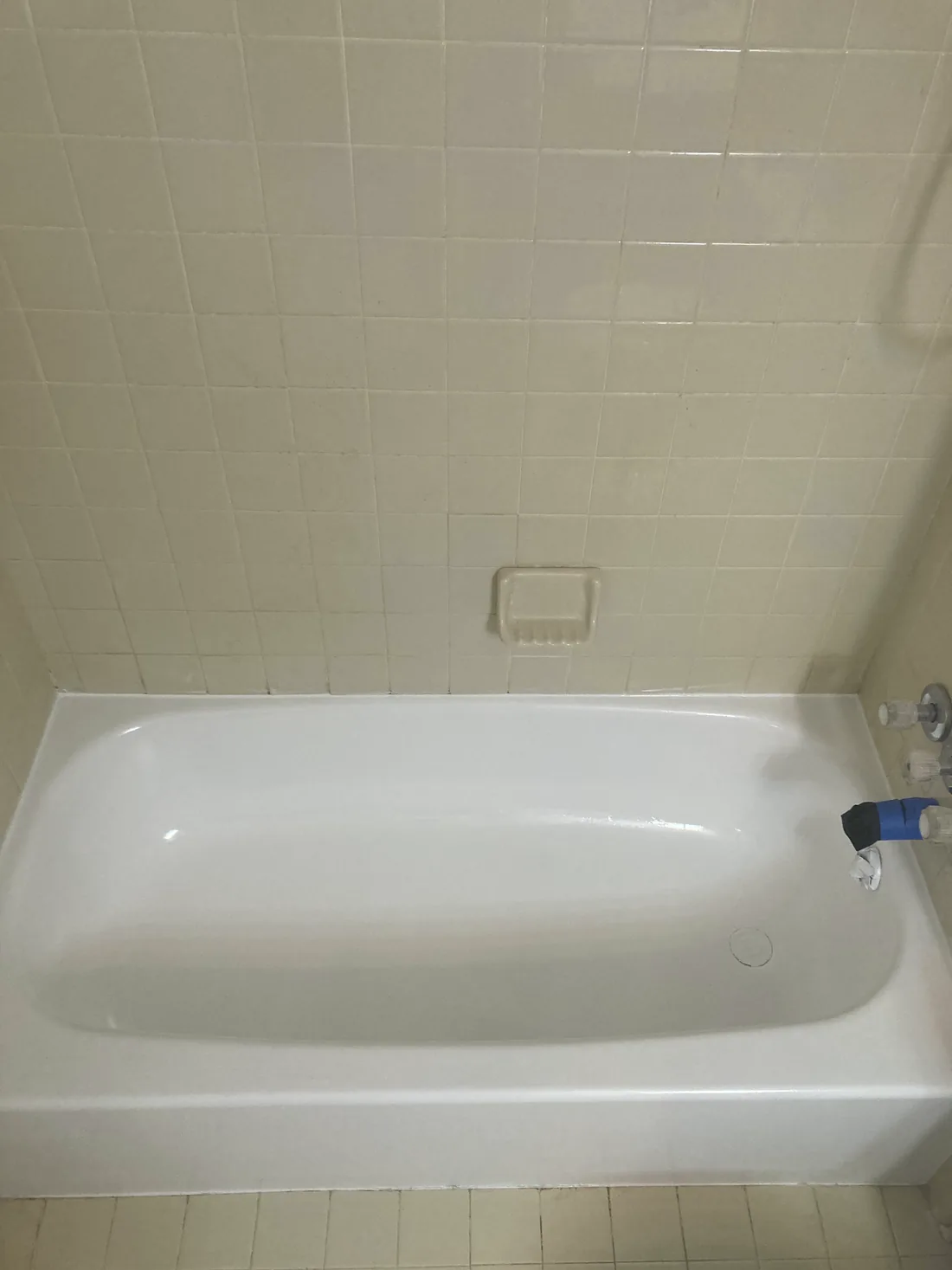 A refinished white bathtub with its tile surround, clean and glossy.