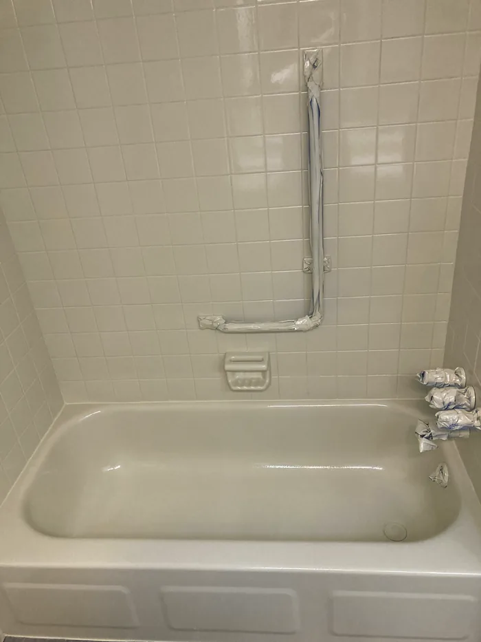 A refinished tub with a grab bar, white and glossy.