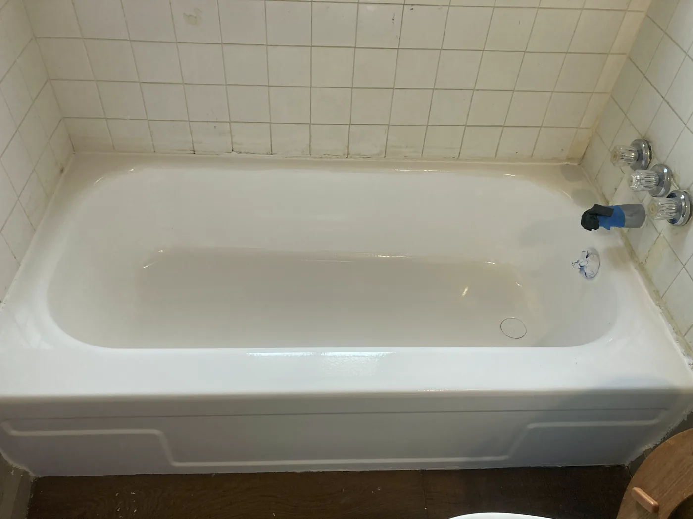 A refinished white bathtub, wide, the whole basin gleaming under the window.