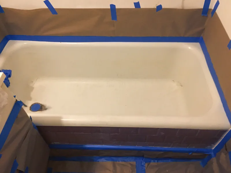 A bathtub masked with brown paper and blue tape ahead of spraying.