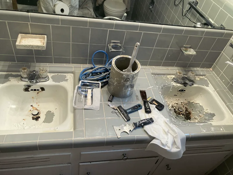 A double sink mid-strip, tools laid on the tile.